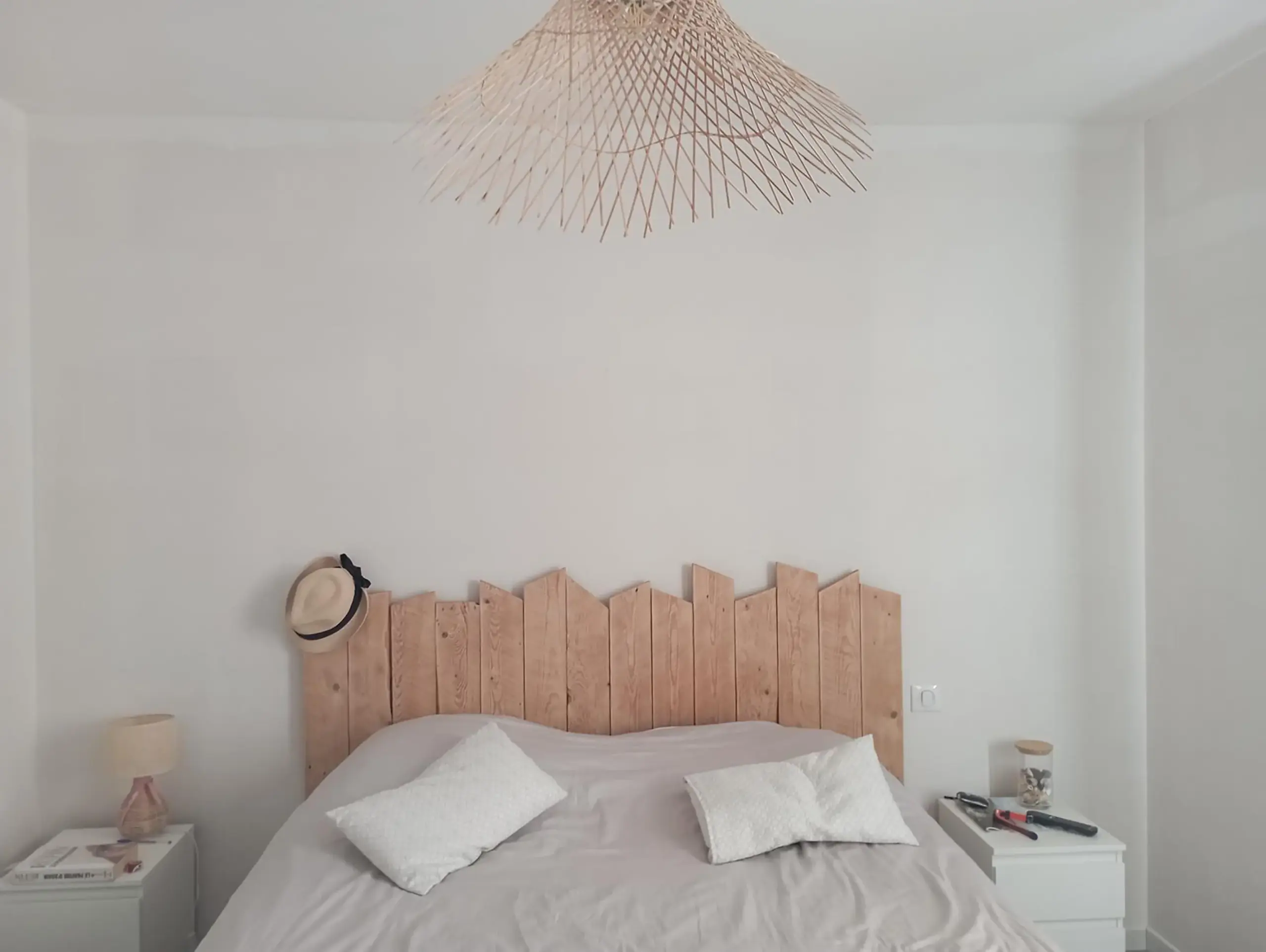 Retour client avant la pose d'un papier peint où le grand mur d'une chambre derrière un lit est vide et blanc.